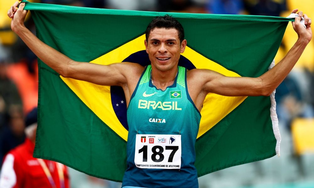 Foto do atleta Altobeli Silva enrolado na bandeira do Brasil.