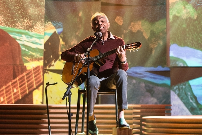 Gilberto Gil no palco, tocando violão e cantando