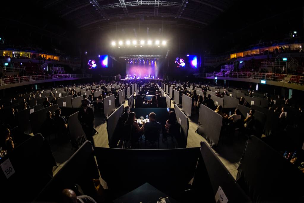 Jeunesse Arena com público acomodado em mesas e boxes separando cada uma delas