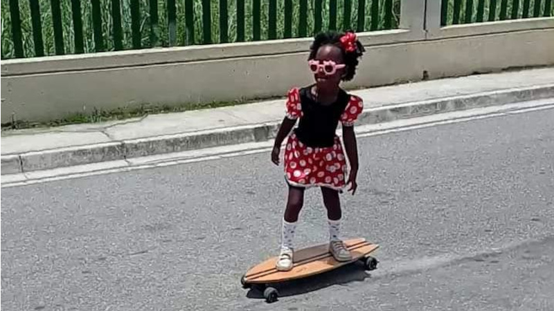 A imagem mostra uma menina vestida como a Minnie, sobre um skatea