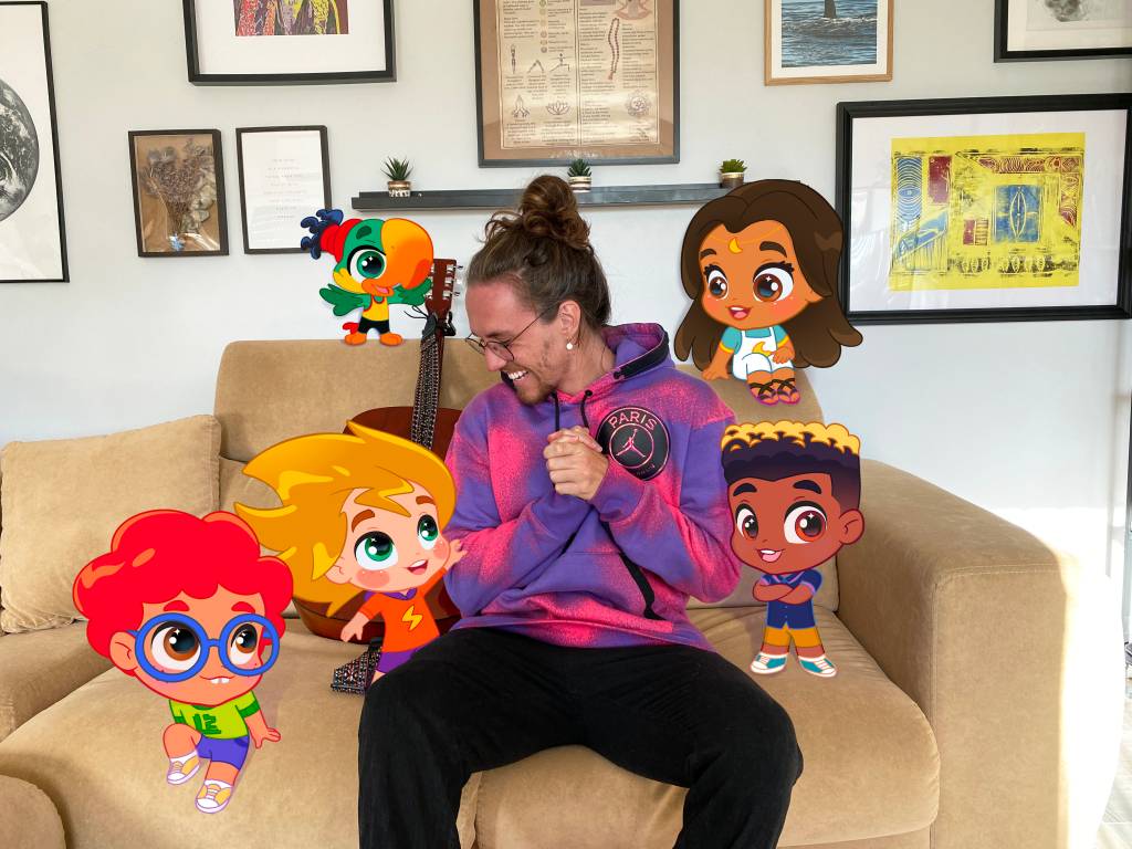 Foto mostra o cantor Vitor Kley em um sofá com personagens animados