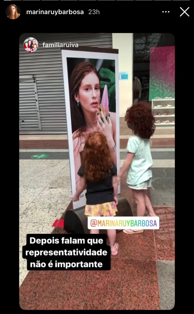 duas crianças ruivas admiram cartaz em que marina ruy barbosa aparece