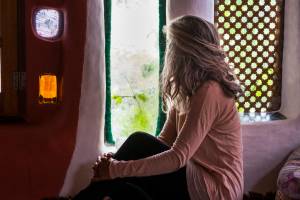Lonely caucasian woman at home look through the window outdoor –