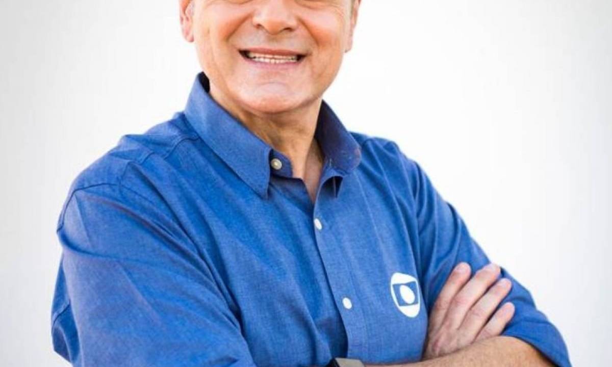 A imagem mostra o narrador Luis Roberto, de camisa azul com o logotipo da TV Globo