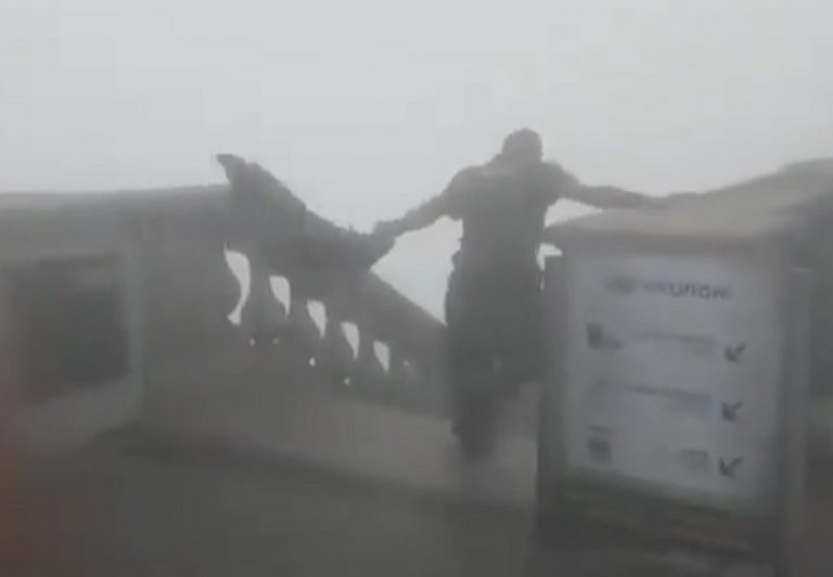 Um funcionário do Cristo redentor luta contra o vento para conseguir descer escadas do monumento
