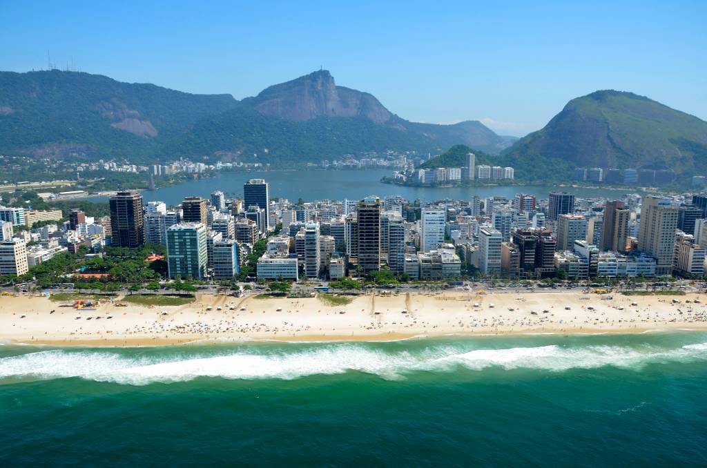 Foto mostra vista aérea do Rio de Janeiro com o mar e prédios