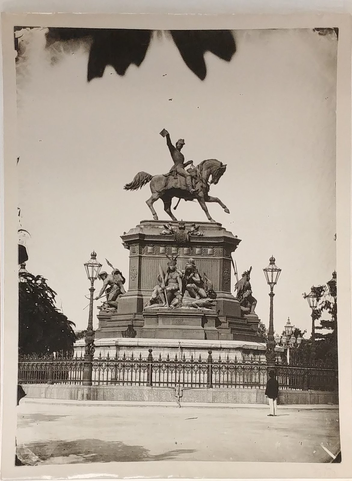 Foto mostra estátua de D Pedro I na Praça Tiradentes com homem de chapéu observando