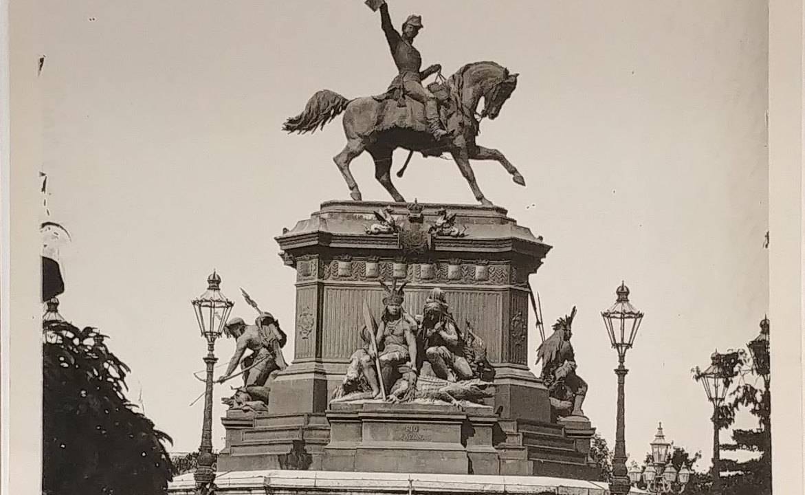 Foto mostra estátua de D Pedro I na Praça Tiradentes com homem de chapéu observando