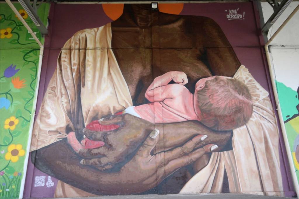 Obra em grafite retrata uma mulher negra amamentando um bebê branco.