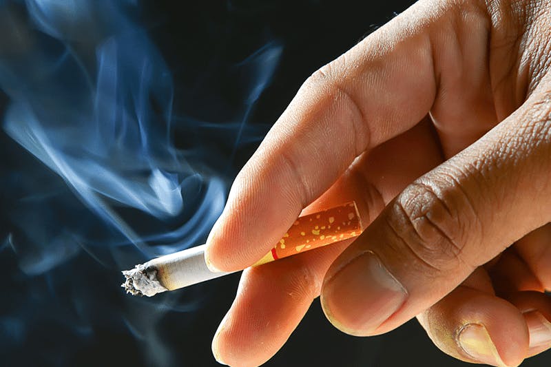 Foto de uma mão segurando um cigarro.