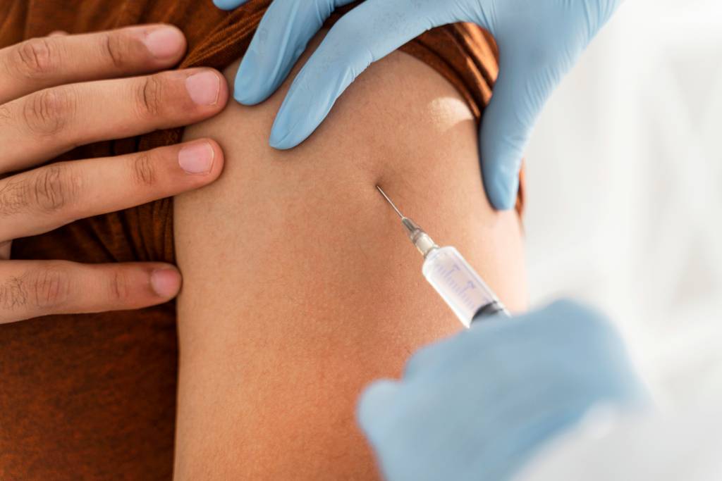 Imagem mostra braço de pessoa recebendo a vacina