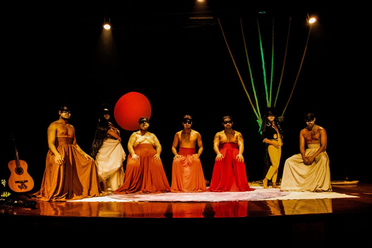 Vários atores vestidos de vermelho em um palco