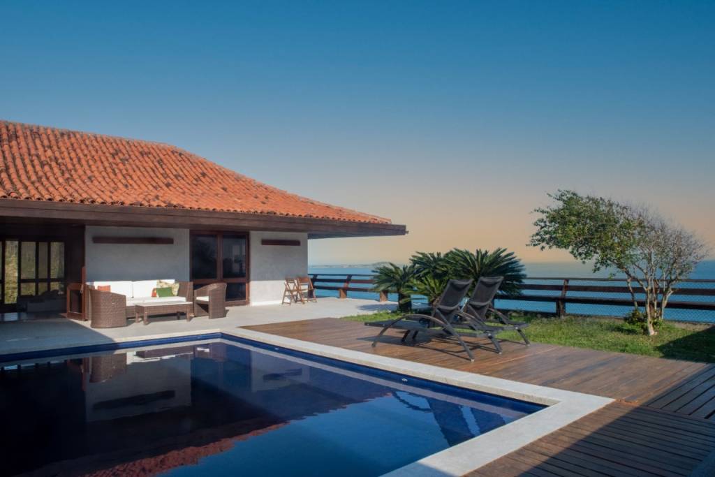 Uma mansão em São Conrado, com piscina azul, jardim e vista para o mar