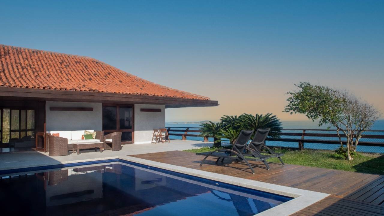 Uma mansão em São Conrado, com piscina azul, jardim e vista para o mar
