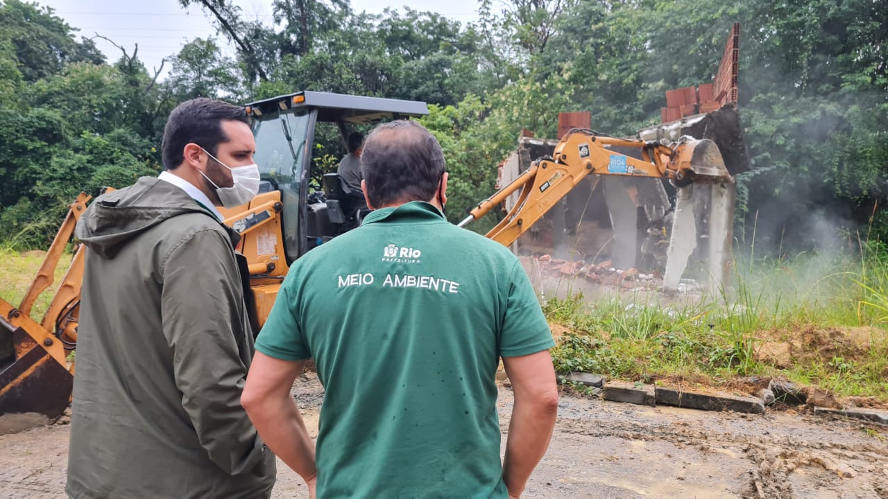 A imagem mostra fiscais observando a demolição de construção irregular em área de proteção ambiental