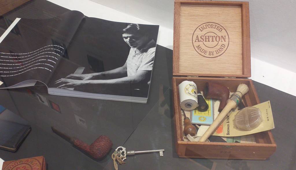 Imagem mostra artefatos de Tom Jobim, como um caximbo, uma caixa e uma foto do músico