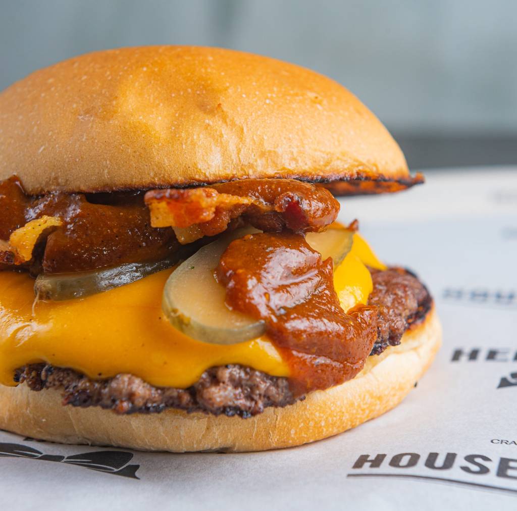 Foto de hambúrguer com queijo cheddar, picles e molho vermelho