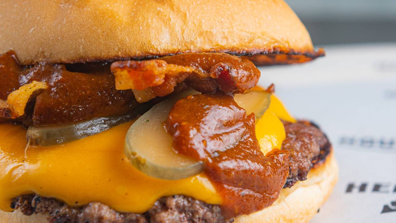 Foto de hambúrguer com queijo cheddar, picles e molho vermelho
