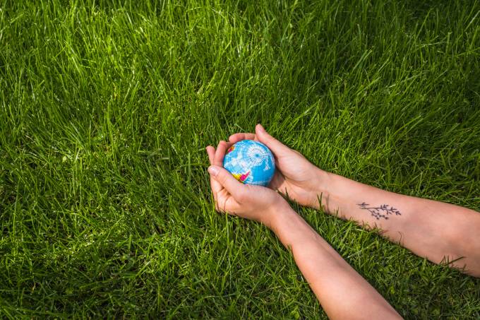 an-overhead-view-of-hands-holding-globe-ball-on-green-grass