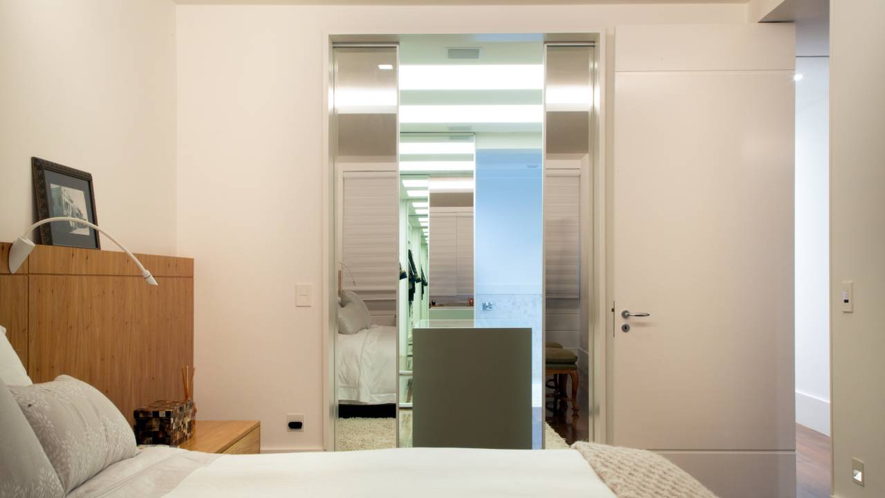 A imagem mostra um quarto com uma porta de correr feita de espelho