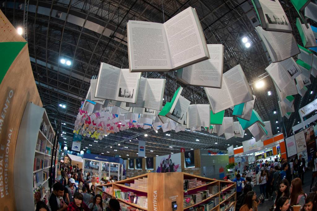 Foto mostra livros gigantes suspensos como decoração na Bienal do Livro