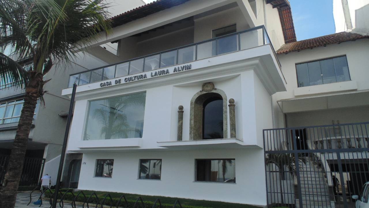 Fachada da Casa de Cultura Laura Alvim, branca, com o nome escrito na frente e uma varanda envidraçada no segundo andar.casa-de-cultura-laura-alvim