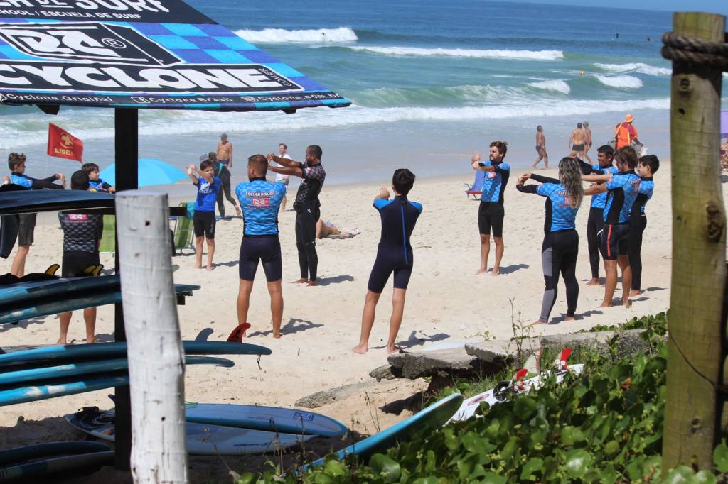 Foto mostra pessoas na aula de surfe na Praia da Barra