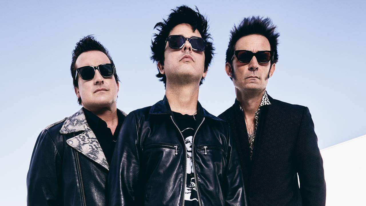Os três integrantes do Green Day com blusas, jaquetas e óculos pretos