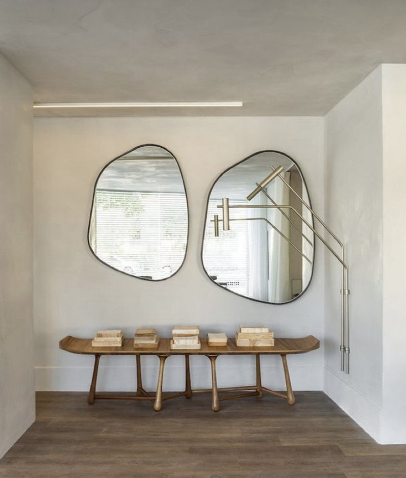 A imagem mostra dois espelhos na parede e um banco de madeira .