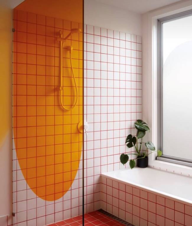 A imagem mostra um banheiro com revestimento branco e rejunte vermelho
