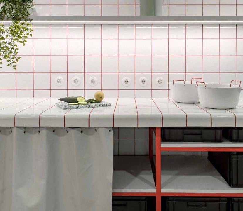 A imagem mostra uma cozinha com revestimento branco e rejunte vermelho