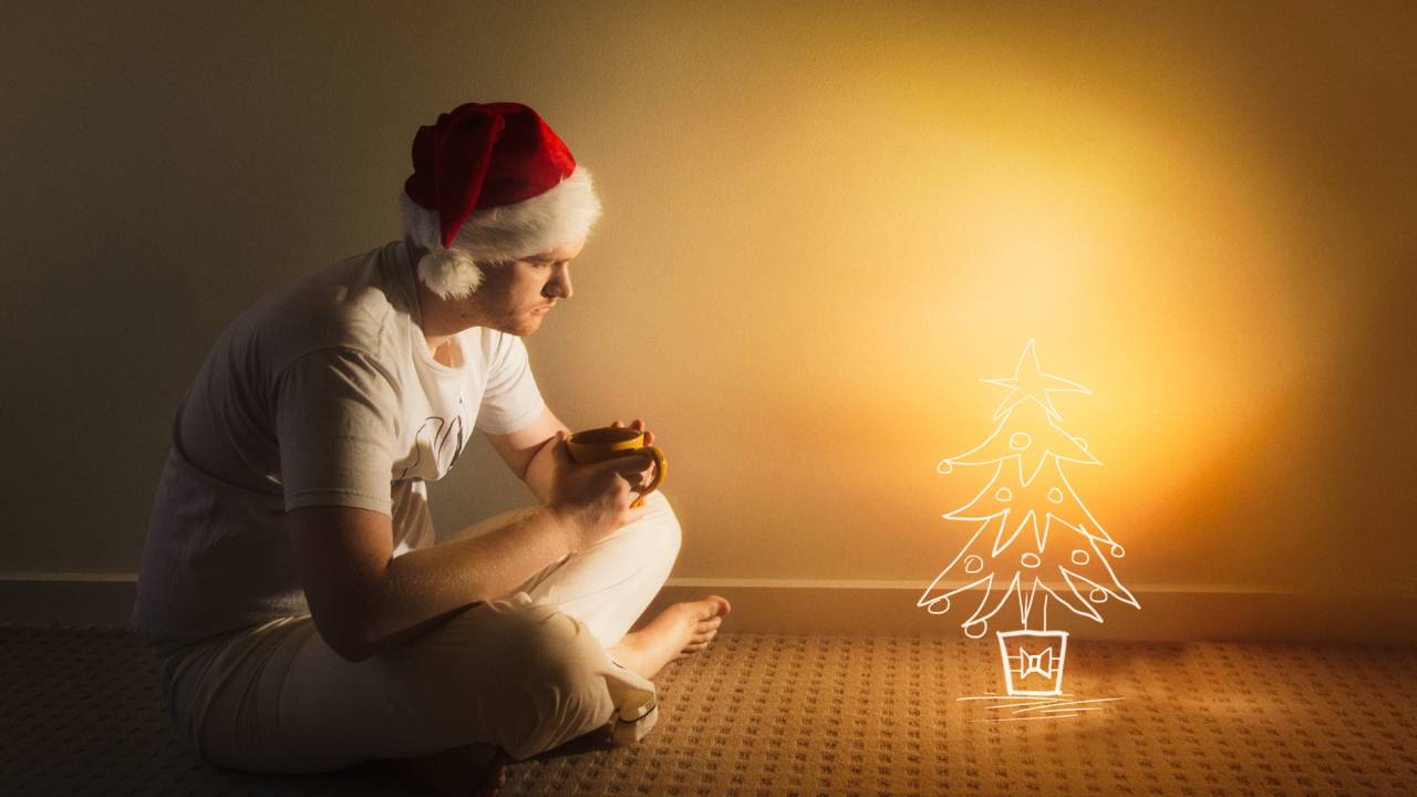 Homem solitário diante de uma árvore de Natal.