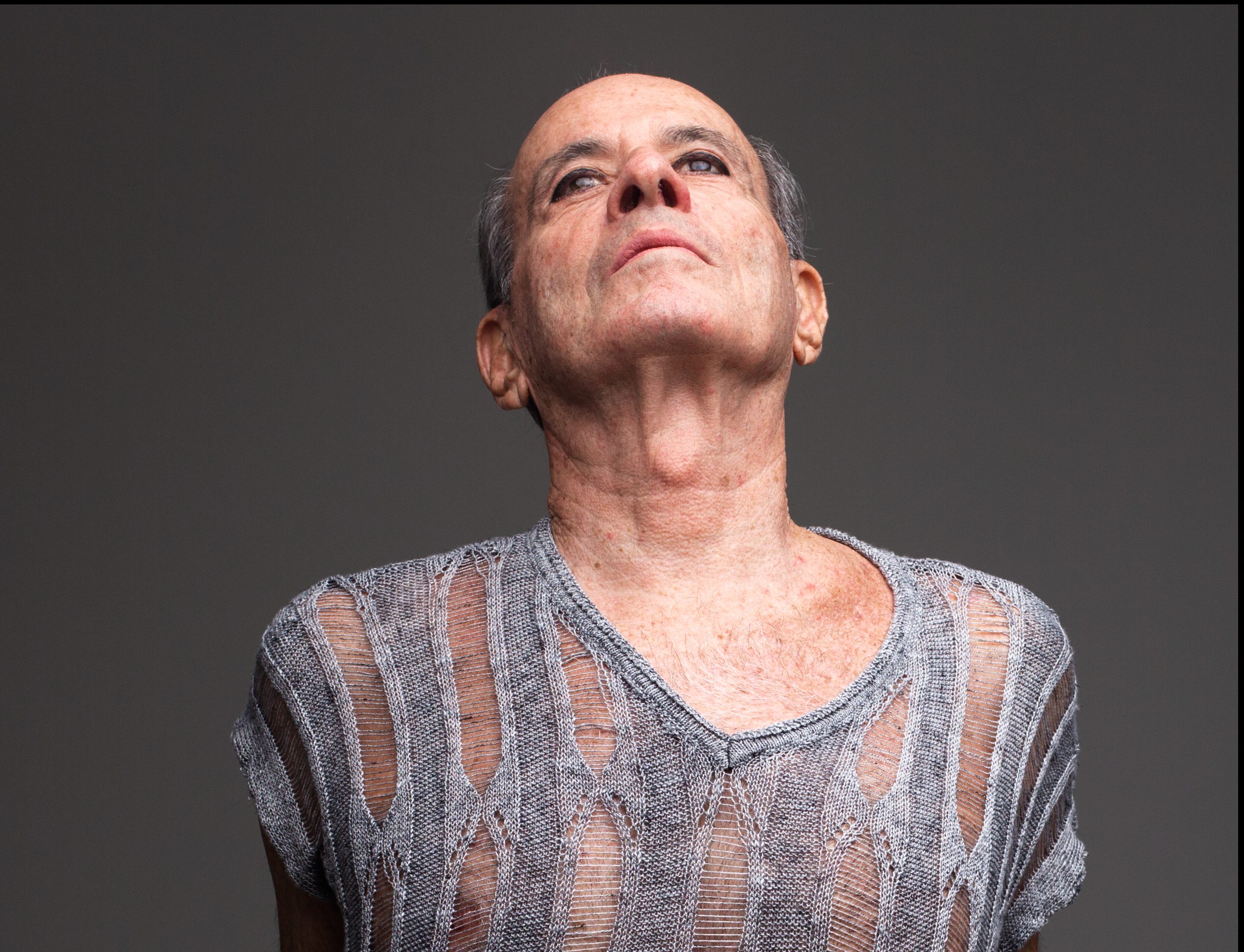 Ney Matogrosso usa blusa cinza listrada com tecido transparente