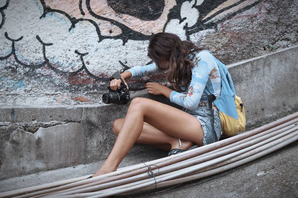 Foto mostra fotógrafa agachada tirando foto com câmera profissional