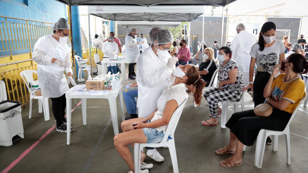 Foto mostra profissionais da saúde realizando testes de Covid em pacientes