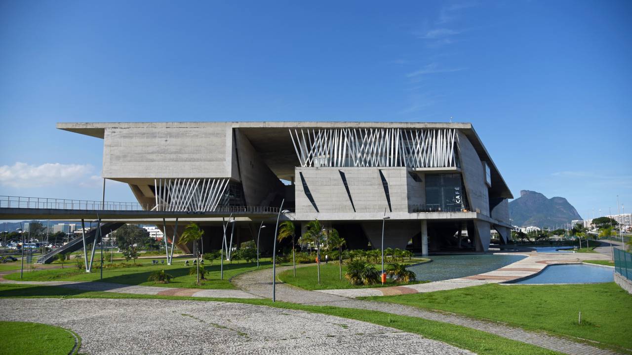 Foto mostra o prédio da Cidade das Artes, uma estrutura cinza e com arquitetura moderna