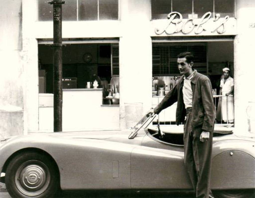 Bob Falkenburg de terno em frente a seu jaguar e à primeira loja do Bob's