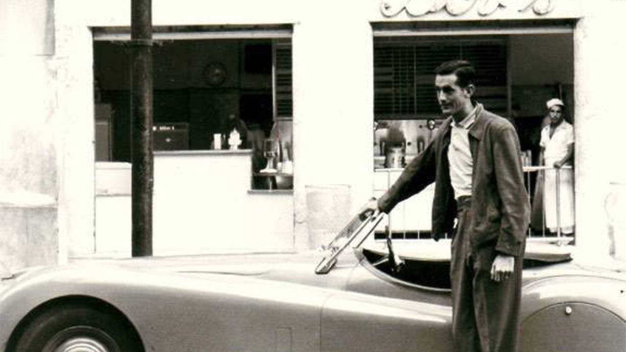 Bob Falkenburg de terno em frente a seu jaguar e à primeira loja do Bob's