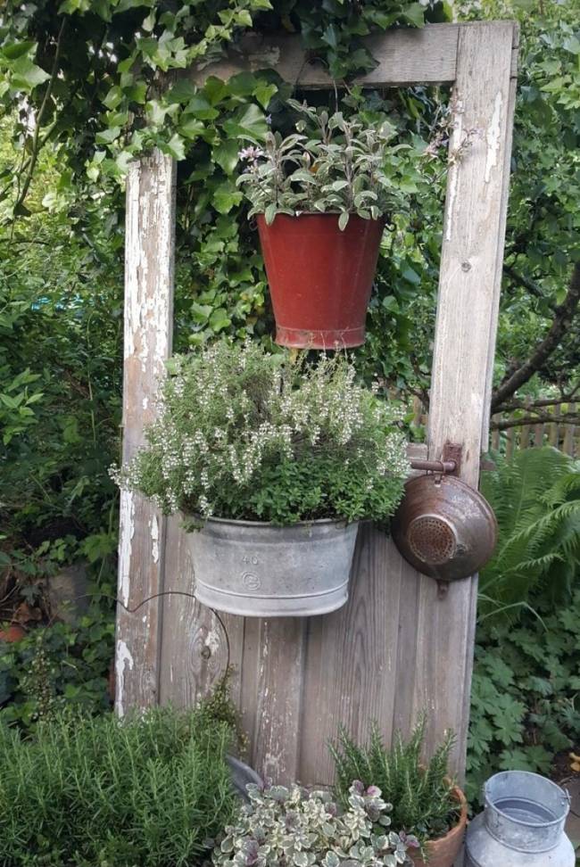 A imagem mostra um jardim e vasos pendurados em uma porta.