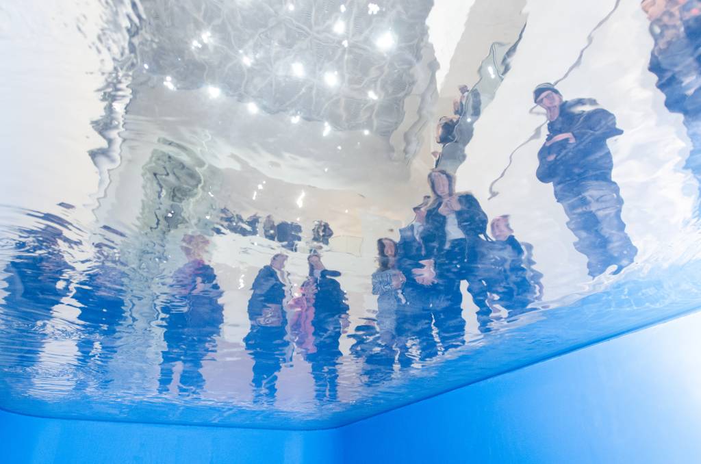 Instalação ilusionista que é uma piscina em que o público pode observar de dois lugares, vista do ponto de vista de quem está embaixo do espelho d'água