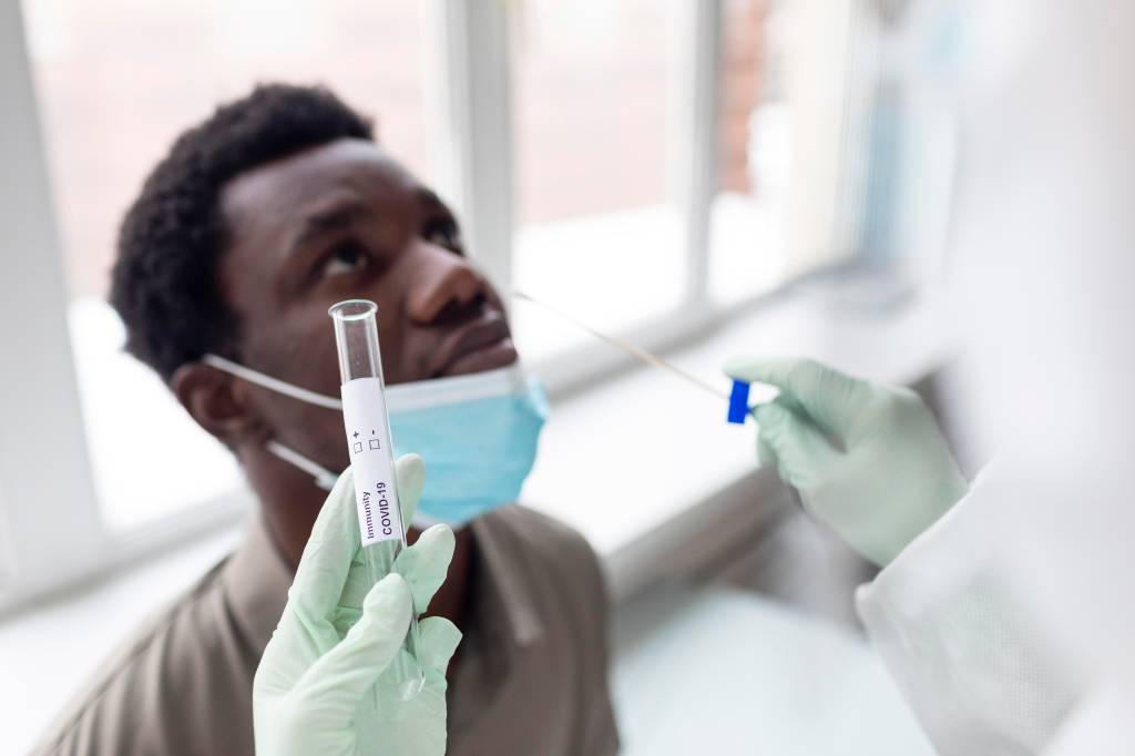 Foto mostra exame PCR sendo realizado em um paciente jovem e negro