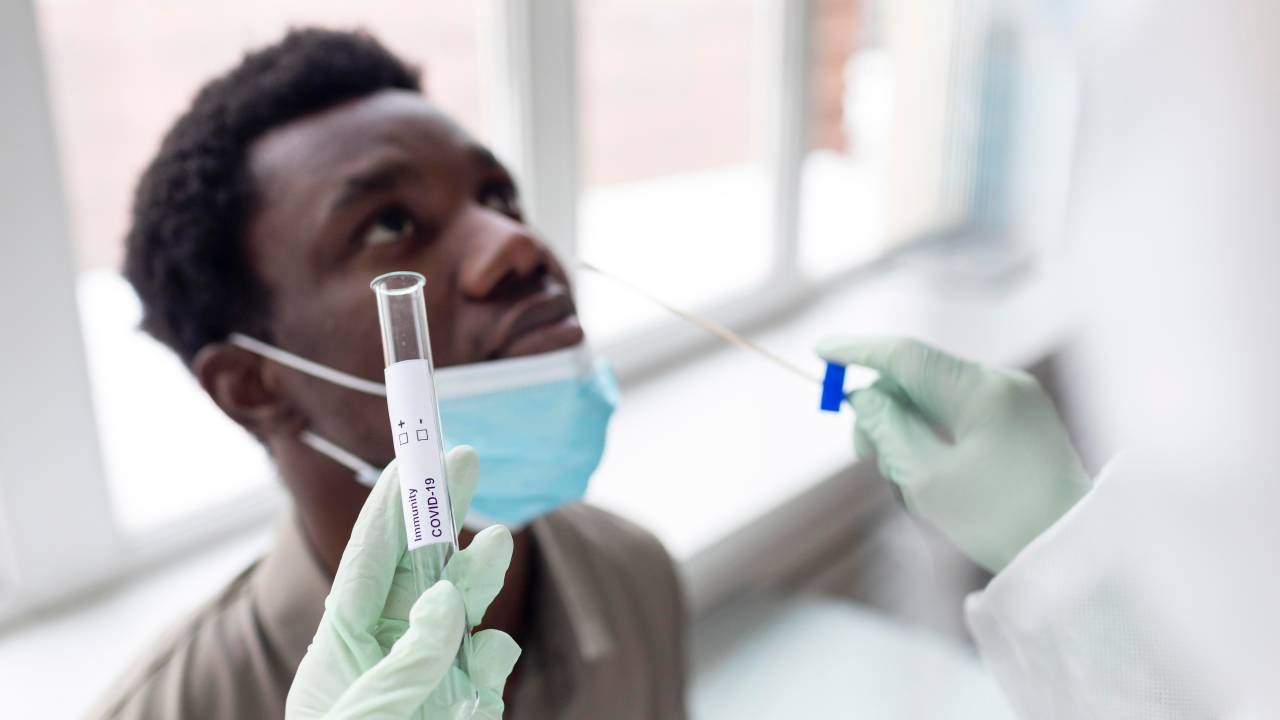 Foto mostra exame PCR sendo realizado em um paciente jovem e negro