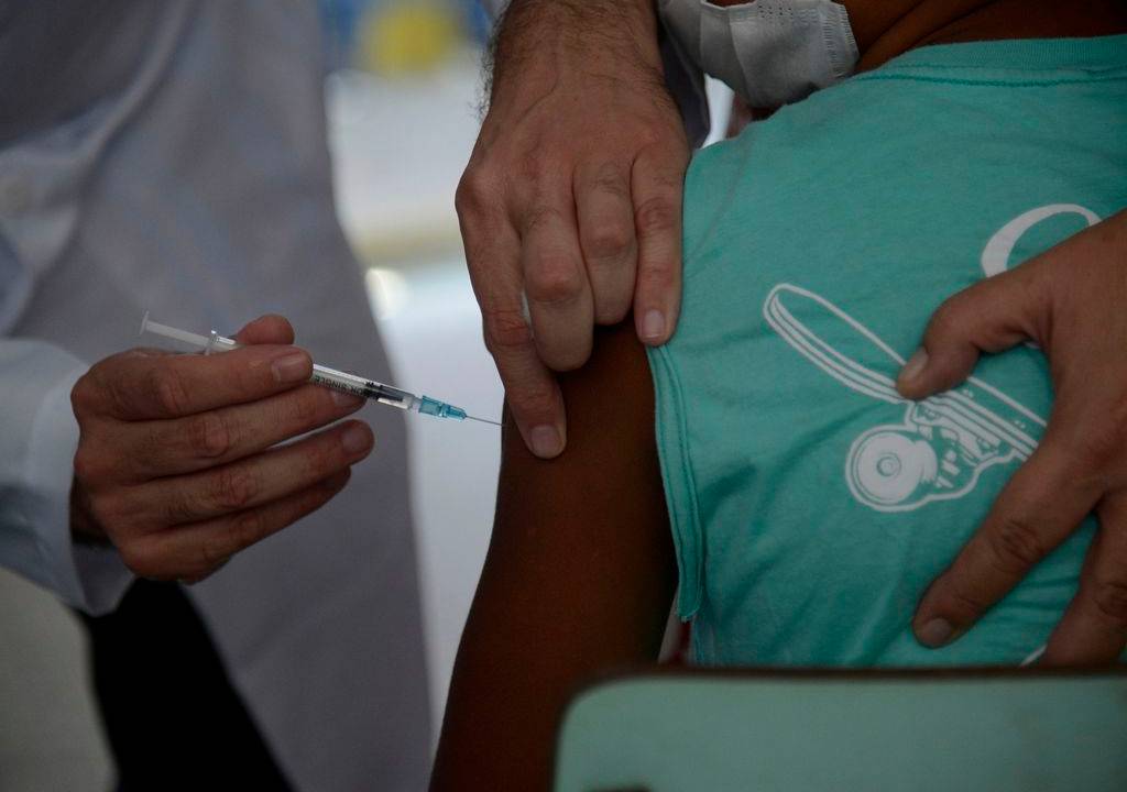 Foto mostra criança recebendo vacina