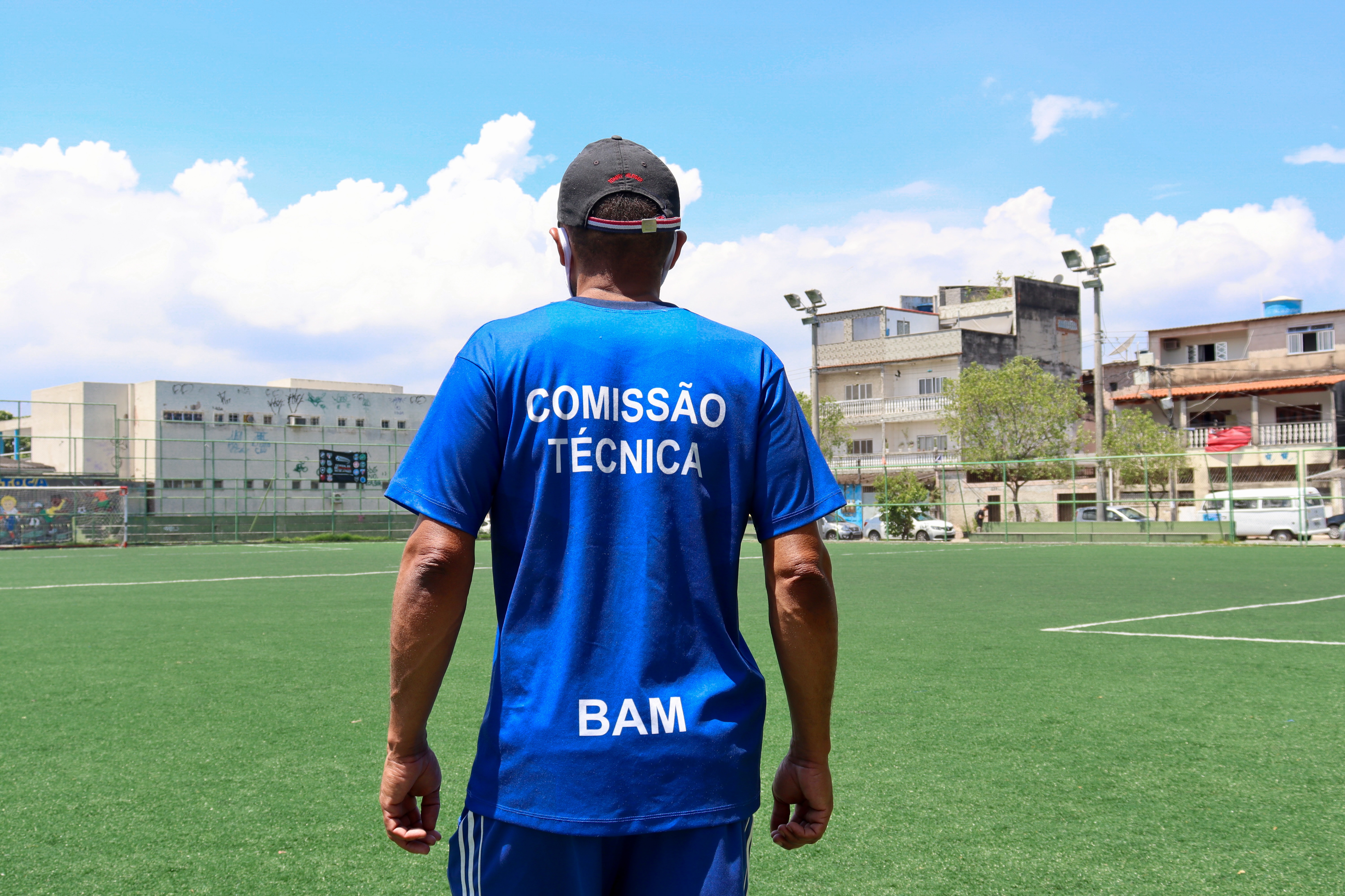 Foto mostra homem de costas com uniforme azul de técnico de futebol