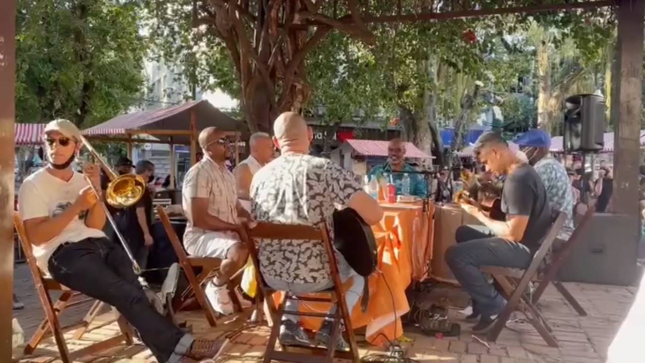 Foto mostra grupo de samba tocando em uma praça