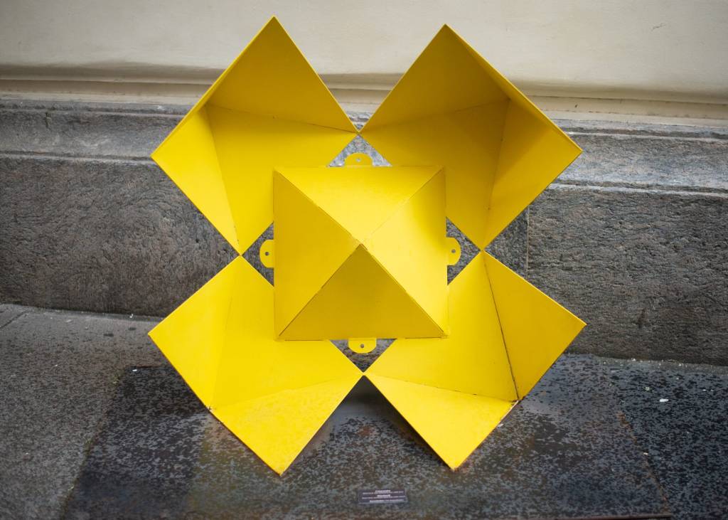 Escultura geométrica amarela feita em metal de Duda Oliveira