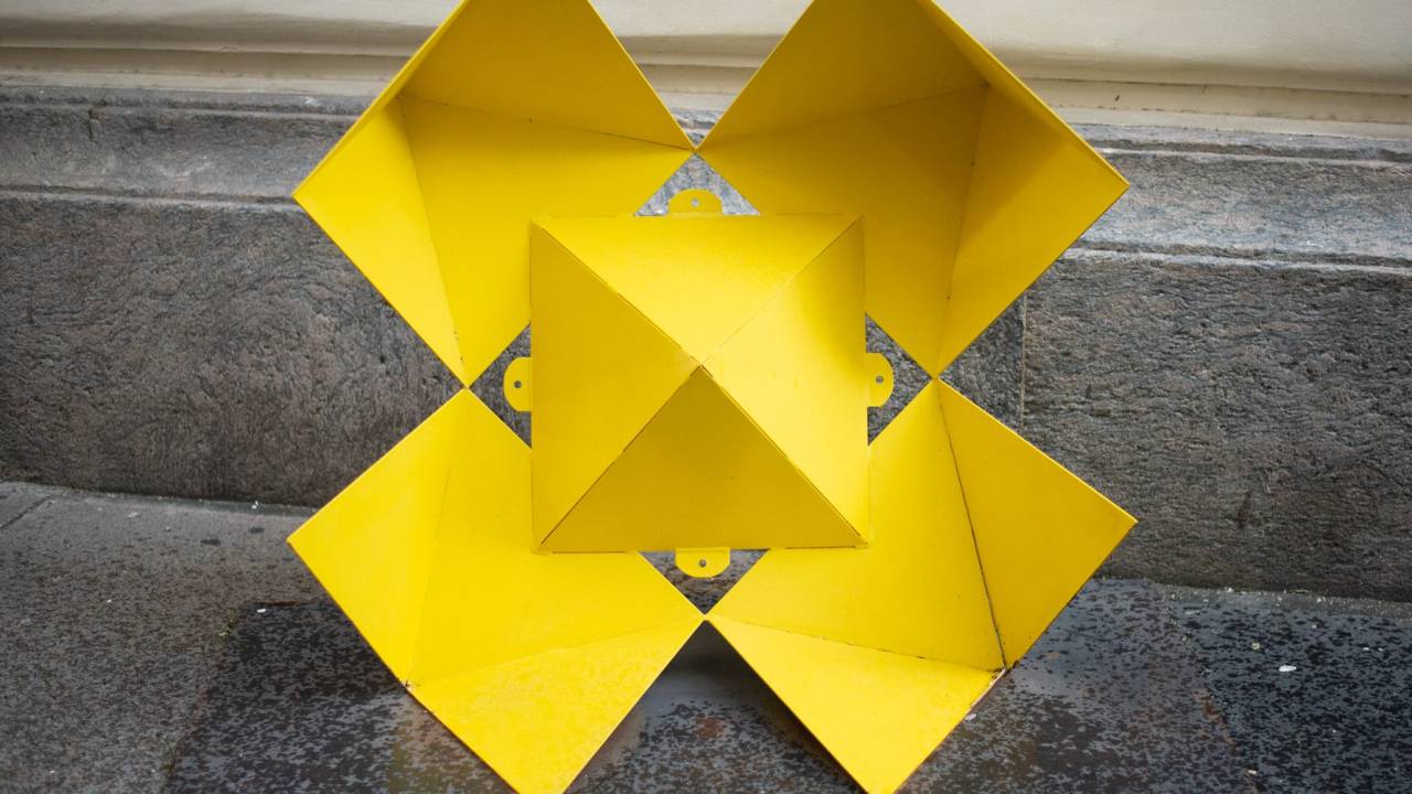 Escultura geométrica amarela feita em metal de Duda Oliveira