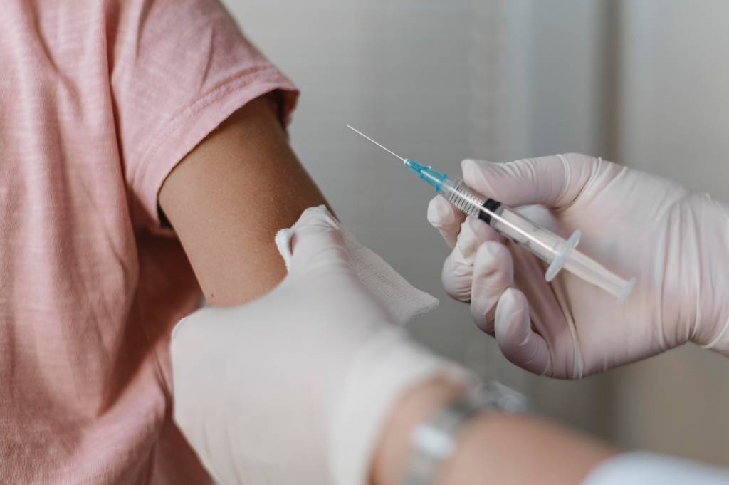 Foto mostra criança com braço tomando vacina