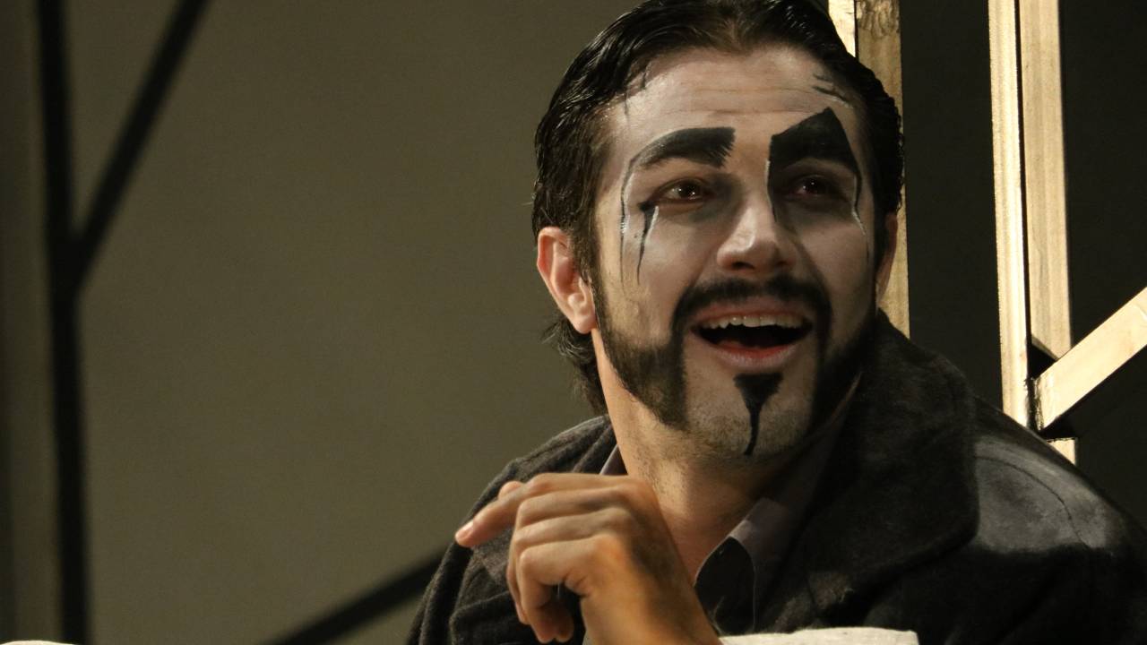 O ator Rômulo estrela com o rosto maquiado de branco e cavanhaque, bigode e sobrancelhas pintados de preto, na peça O Alienista
