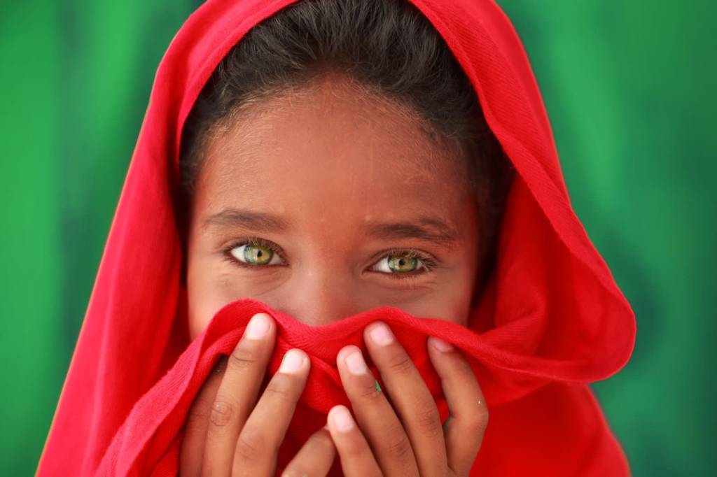 Foto mostra menino negro com olhos verdes coberto com turbante vermelho